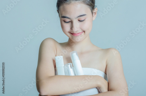 Smiling Woman Holding Skincare Bottles with Eyes Closed in Relaxation