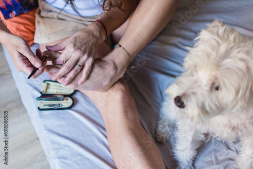 Woman using a cuticle pusher on her toe nail photo