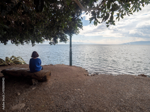 Young girl watching the Sea of Galilee seen at Capernaum, Israel photo