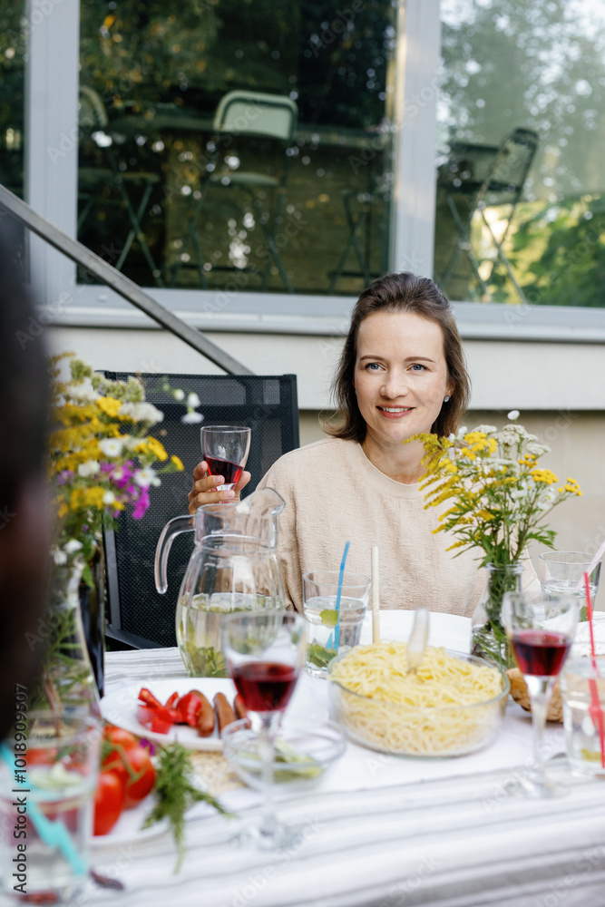 Woman with wine resting and having lunch at table with partial friend Woman with wine resting and having lunch at table with partial friend