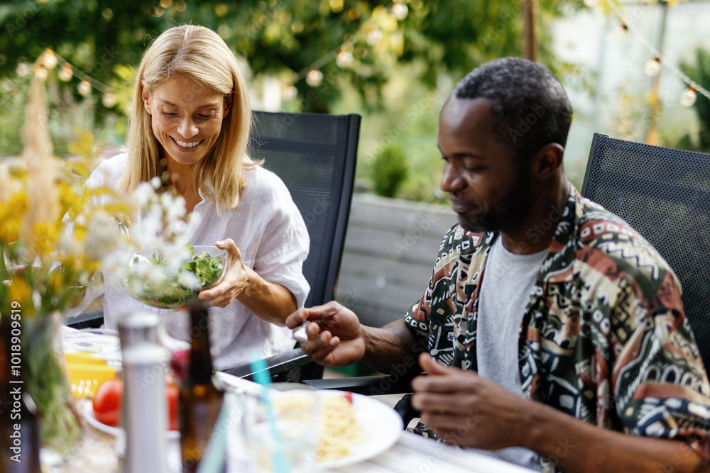 Happy multiracial couple resting and having lunch at table on terrace Happy multiracial couple resting and having lunch at table on terrace