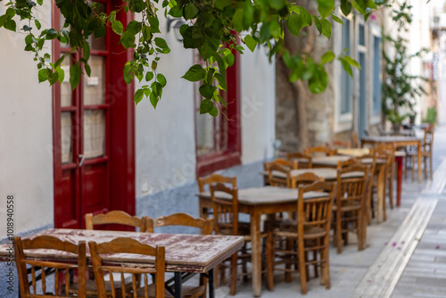 Fototapeta Naklejka Na Ścianę i Meble -  Rustic wooden tables and chairs create an inviting atmosphere in Nafplio, Greece, inviting visitors to relax and savor local delicacies in this picturesque setting.