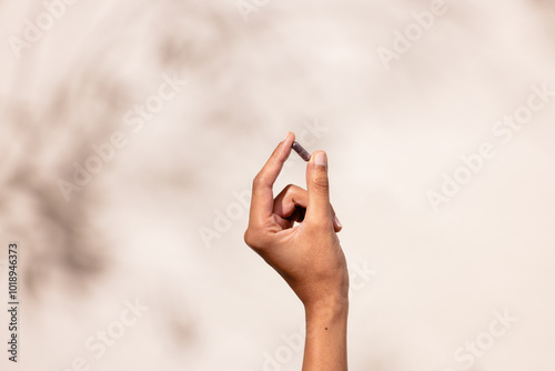Hand Holding Pill Against Blurred Background