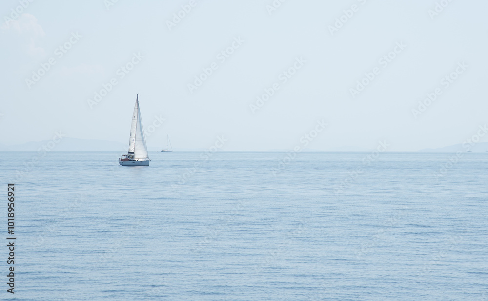 Sailboat with mast and open sails is sailing on a calm sea. Greek Islands, Ionian Sea Sailboat with mast and open sails is sailing on a calm sea. Greek Islands, Ionian Sea