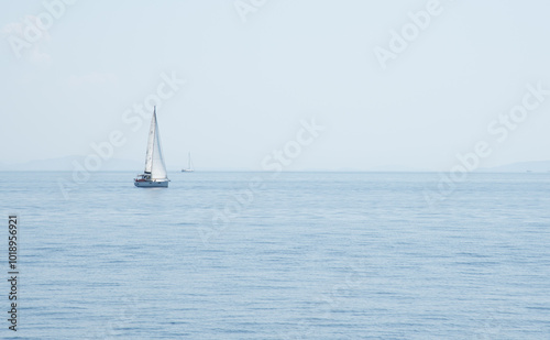 Sailboat with mast and open sails is sailing on a calm sea. Greek Islands, Ionian Sea