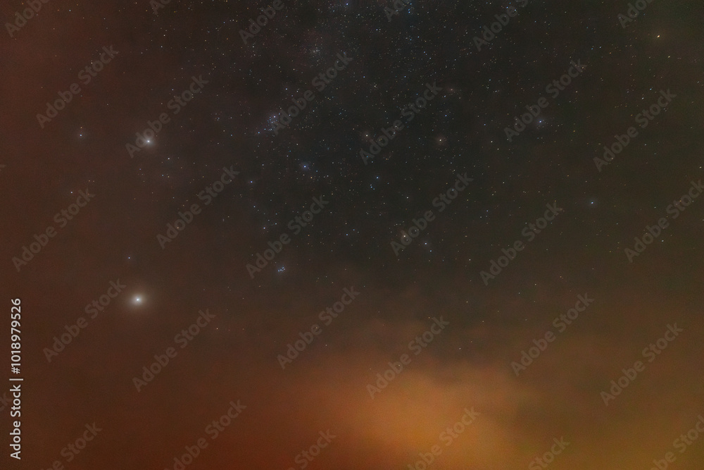 Obraz premium A peaceful night sky filled with faint stars and a soft red aurora glow near the horizon. The cosmic scene blends dark space with atmospheric colors, creating a dreamy, tranquil view.