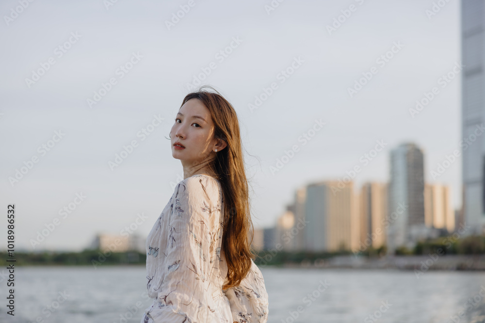 Woman looking back by a city waterfront Woman looking back by a city waterfront