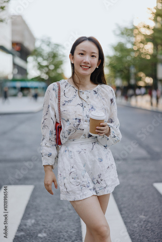 Woman holding coffee cup and walking on a city street photo