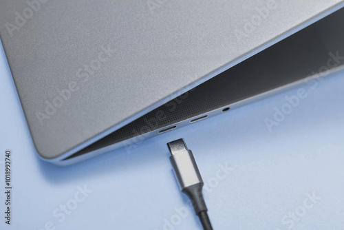 Grey netbook laying on blue surface next to micro usb wire photo