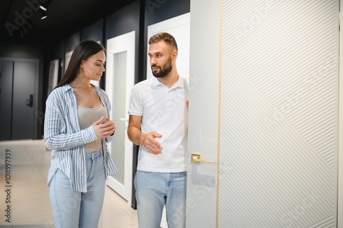 Portrait of smiling young man and woman shopping in the hardware store choosing different door options photo