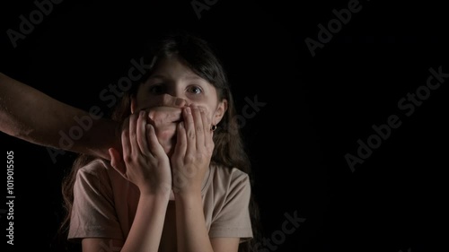 The man covers the child's mouth with his hand. A view of man put her palm on child mouth to stop speaking. A concept of interdiction or taboo during childhood.