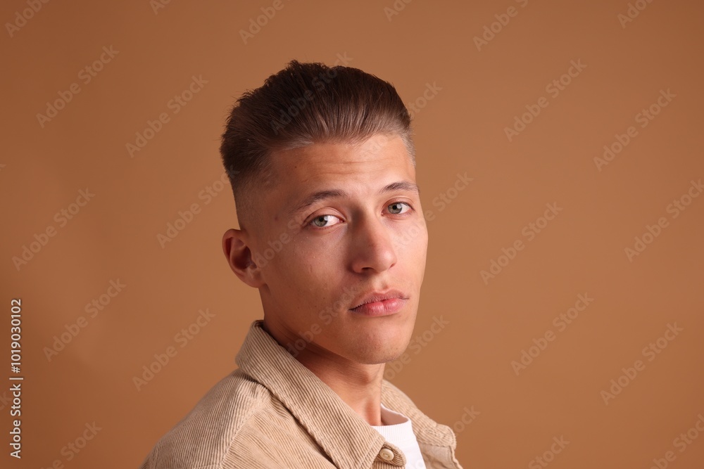 Confident young man with stylish haircut on brown background Confident young man with stylish haircut on brown background