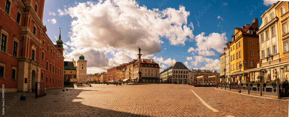 Panoramic view of Warsaw's historic market square under a vibrant blue sky with scattered clouds, showcasing colorful historic buildings and a lively atmosphere.