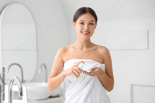Young woman in towel applyi...