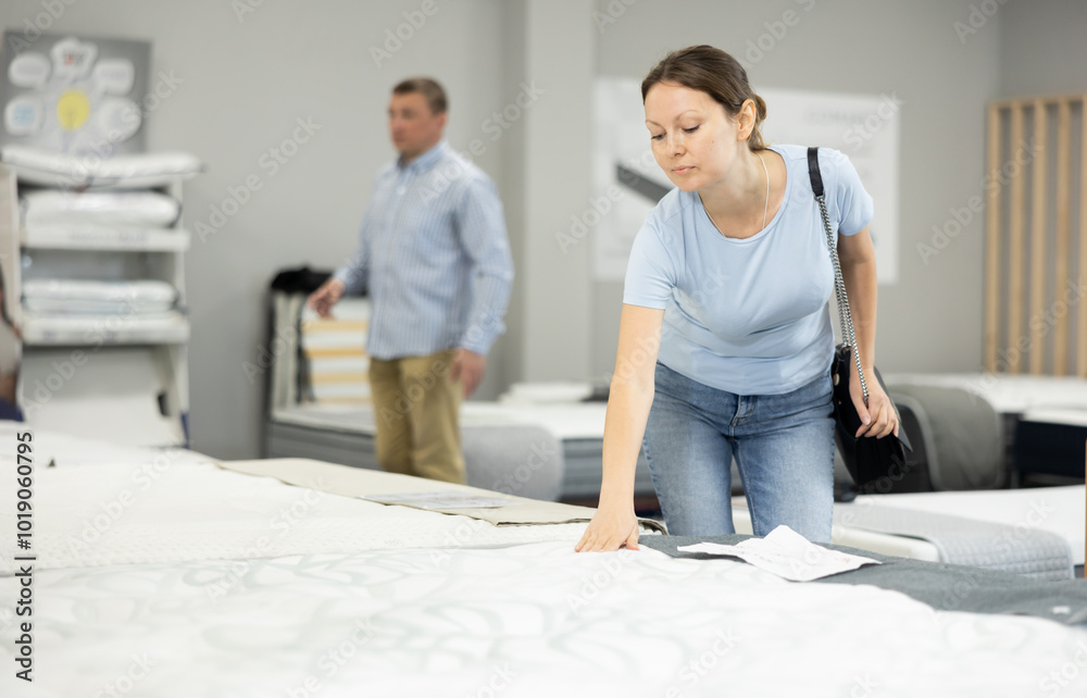 Obraz premium Joyful woman in furniture center chooses best sofa for her apartment