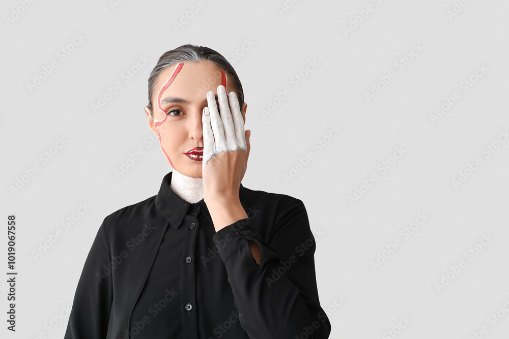 Young woman with painted face on light background Young woman with painted face on light background