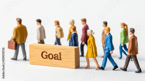 Miniature figures walking towards a wooden block labeled 'Goal', symbolizing ambition and teamwork.