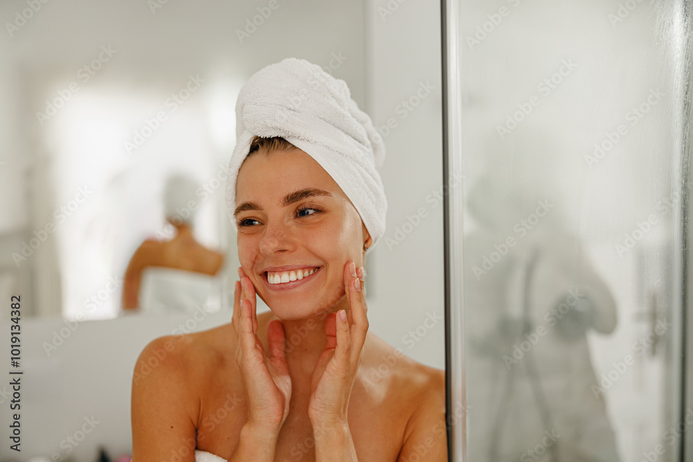 A cheerful woman is happily enjoying her skincare routine after taking a refreshing and revitalizing shower A cheerful woman is happily enjoying her skincare routine after taking a refreshing and revitalizing shower