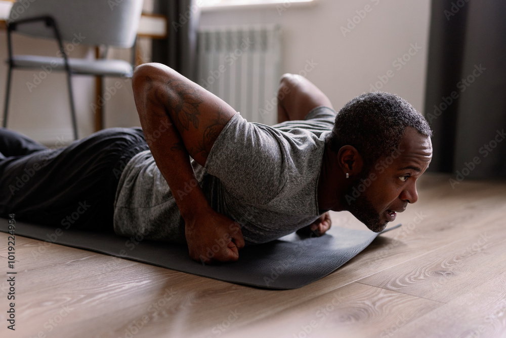 © Oleksii Syrotkin/Stocksy - Focused adult black man doing workout exercise on fitness mat at home © Oleksii Syrotkin/Stocksy - Focused adult black man doing workout exercise on fitness mat at home