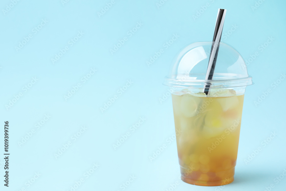 Tasty bubble tea in plastic cup on light blue background, space for text Tasty bubble tea in plastic cup on light blue background, space for text