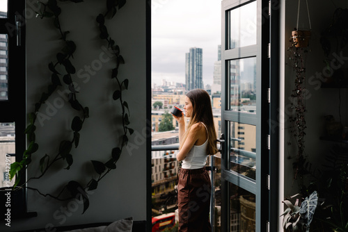 A female vacationer admires the view of London while sipping a coffee