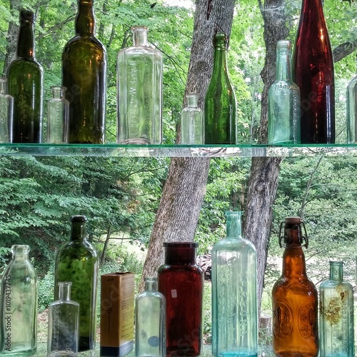 Antique Colored Glass Bottles Lined Up in Window Sil photo