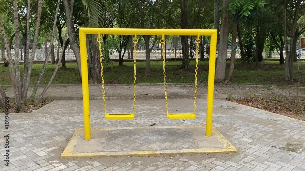 A lonely yellow swing hangs in an empty garden, creating a wistful and nostalgic atmosphere. A lonely yellow swing hangs in an empty garden, creating a wistful and nostalgic atmosphere.