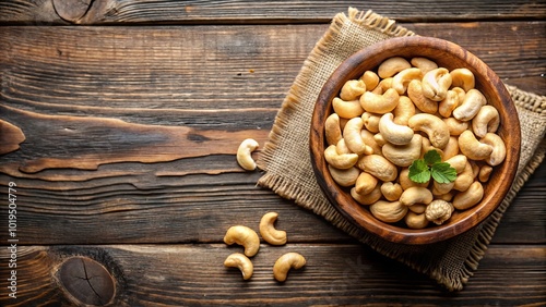 A bowl of roasted cashew nuts on a rustic wooden surface with a burlap napkin, adding a touch of natural elegance to the setting.