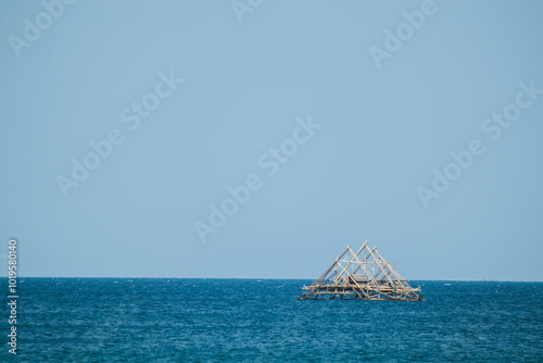 Traditional Floating Bagan Amidst Vast Blue Ocean. Serene Summer Waves Under Bright Blue Skies. Traditional fish aggregating device, bamboo fish trap. photo