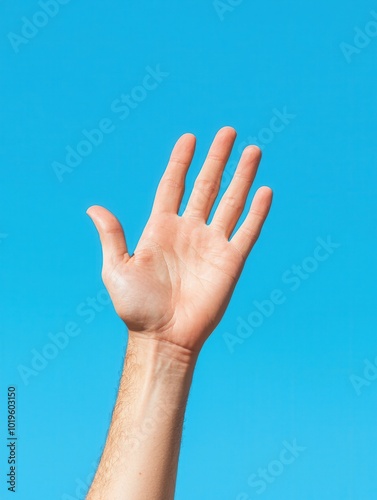 A raised hand against a clear blue sky, symbolizing greeting or reaching out.