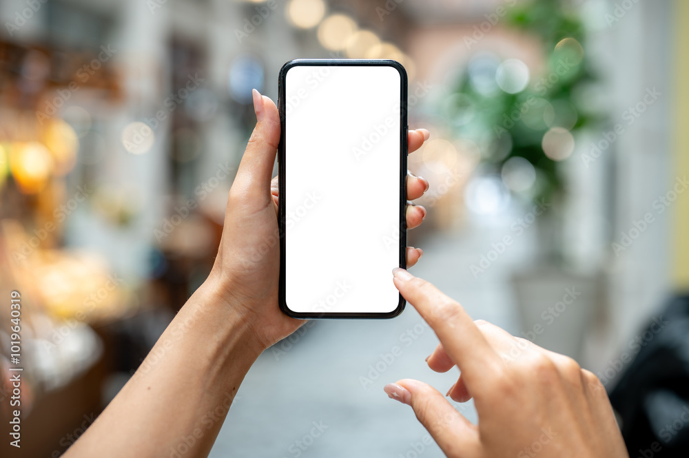 A woman's hand holding a smartphone, set against a blurred background of a market or mall. A woman's hand holding a smartphone, set against a blurred background of a market or mall.
