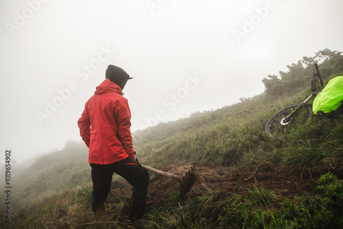 Men builds bike trail in foggy mountains. photo