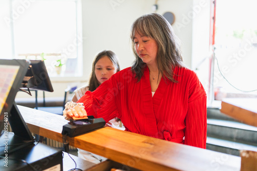 Mother and Daughter Paying with Credit Card at Cash Register photo