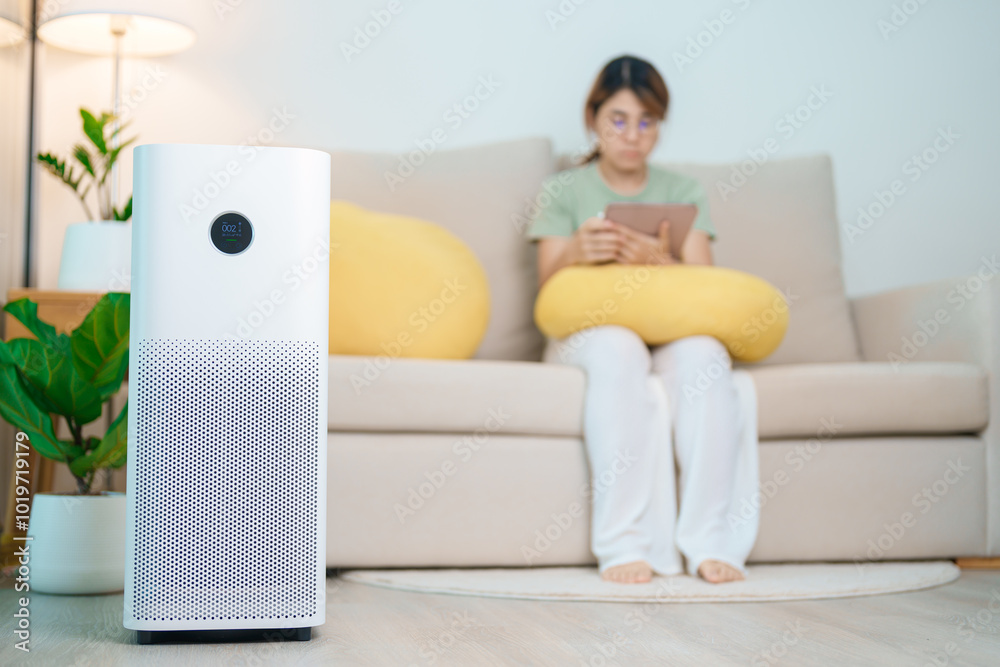 Air Purifier with woman relax and use tablet on sofa. Purification system for filter and cleaning dust PM2.5 HEPA and virus in home. Allergy, Pure air, health, Wellness lifestyle and Air Pollution Air Purifier with woman relax and use tablet on sofa. Purification system for filter and cleaning dust PM2.5 HEPA and virus in home. Allergy, Pure air, health, Wellness lifestyle and Air Pollution