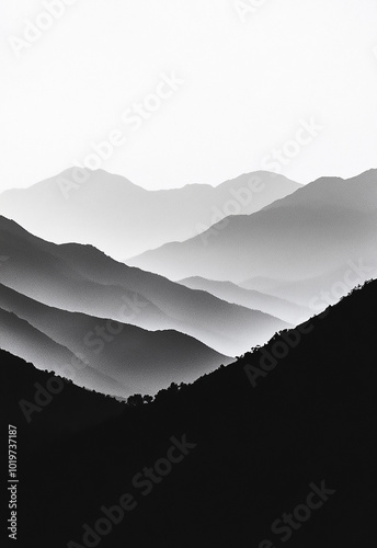 A black and white photograph showcasing a stunning view of mountain silhouettes against a misty backdrop