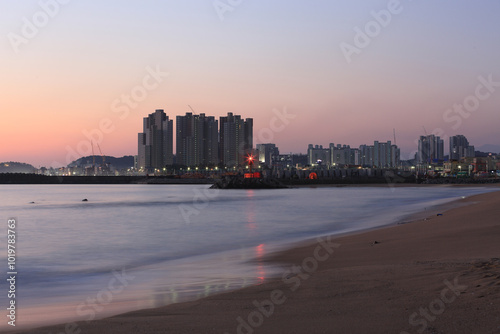 Sokcho-si, Gangwon-do, Korea - February 1, 2020: Panoramic view of Cheongho Beach against apartments under construction before sunrise photo