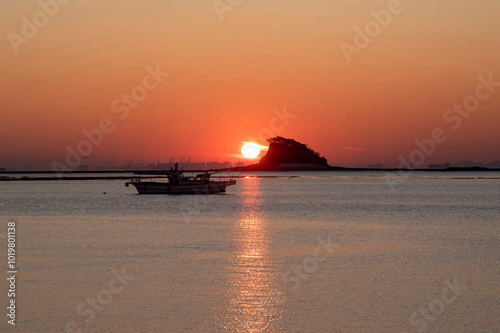 Yeongjongdo, Jung-gu, Incheon, Korea - December 6, 2019: Sunrise over a fishing boat with the Shark Island in the background.  photo