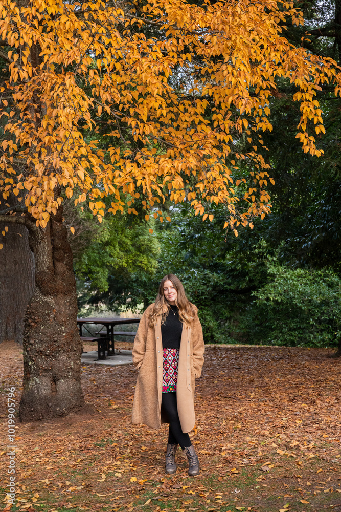 Woman standing under autumn tree in a park in Victoria Australia Woman standing under autumn tree in a park in Victoria Australia