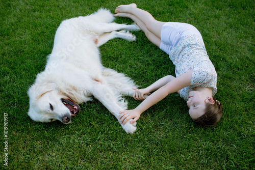 a girl lies with a dog on the grass photo