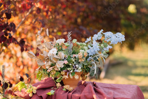 Autumn-hued floral bouquet in rustic pot on table. photo