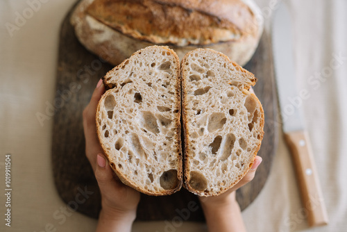 Hand holding sliced sourdough bread on cutting board. photo