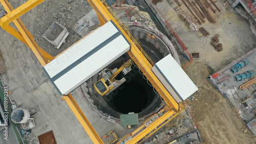 excavator lowered by crane into subway tunnel shaft