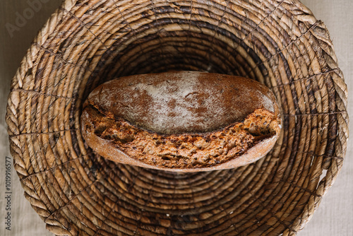 Loaf of freshly baked bread in a woven basket top view photo