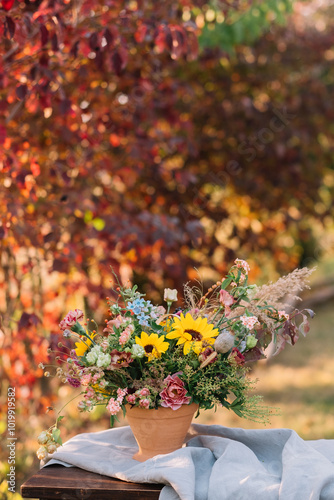 Sunflower arrangement with varied flowers in terracotta pot. photo