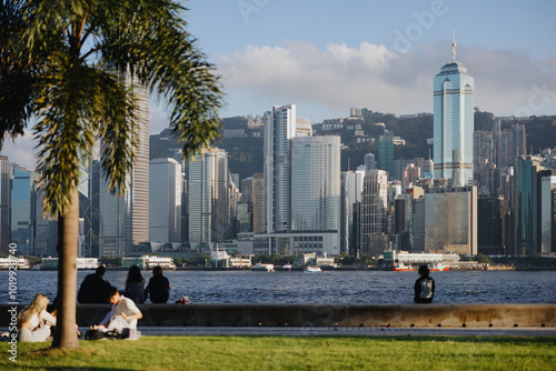 People Relaxing in Park with City Skyline Across the Water photo