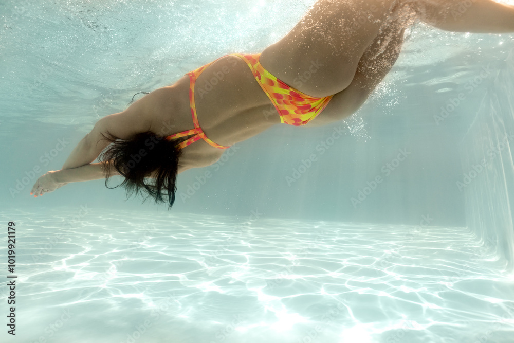 © Andriy Bezuglov/Stocksy - Woman is posing underwater in sunny swimming pool