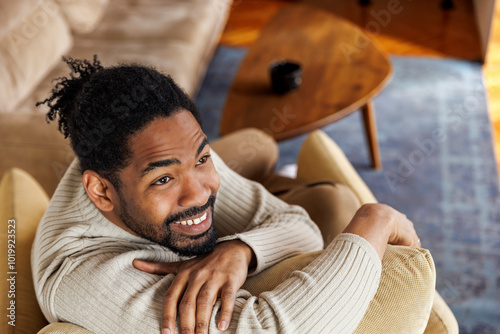 Happy man sitting on couch in living room photo