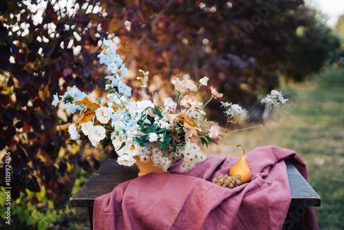 Floral arrangement with a pear on a cloth outdoors. photo