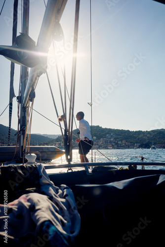 Man walking along the deck of a sailboat photo