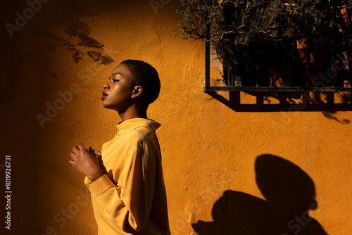 Black Woman in Yellow Shirt and her shadow on wall photo